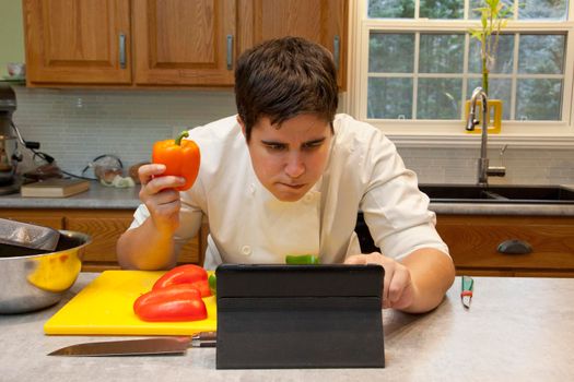 Chef in the kitchen with vegetables looks at their tablet to get a recipe