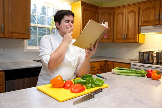  Person in their kitchen looking at a cookbook and considering a recipe