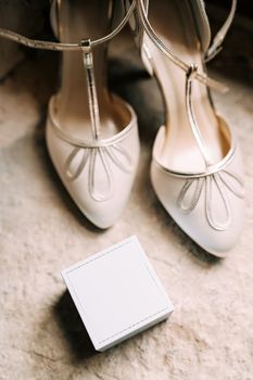 Women's white shoes and a box for rings on a stone texture. High quality photo