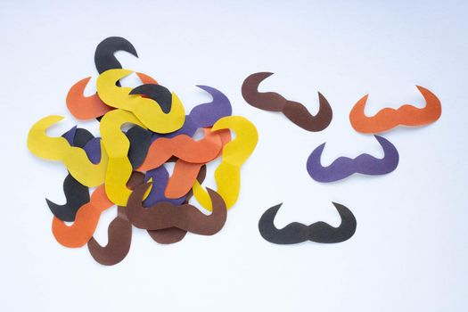 On a white background, there are many colorful paper mustaches. Father's Day, party decoration concept.
