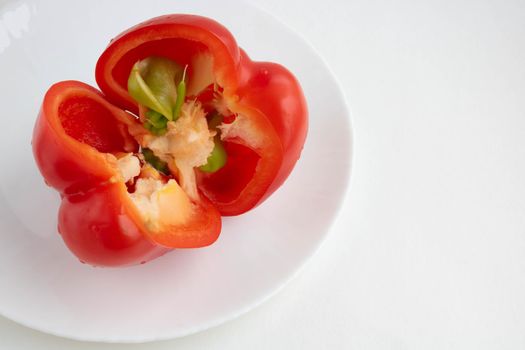 Red sliced pepper on a white plate, isolated on a white background. Space for your text.