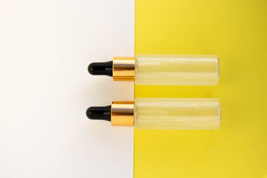Two bottles of cosmetic liquid transparent gel on a white yellow background. Flat styling style.
