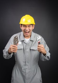 yell young mechanic in suit with wrench on black background background