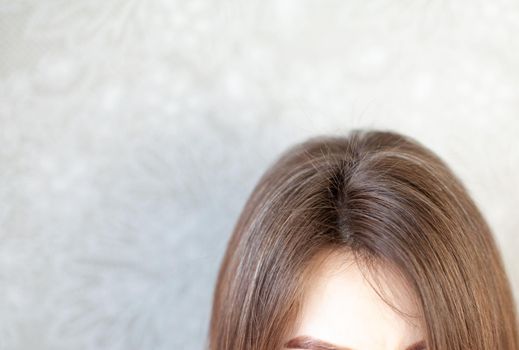 The head of a woman with a parting of gray hair. A woman does her hair. Brown hair on a woman's head close-up.