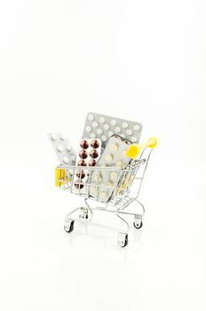 capsules,pills,medicines in blisters on white background in shopping cart. Pharmacy,people and health concept.Online ordering of medicines,online shopping.Vitamins and dietary supplements.