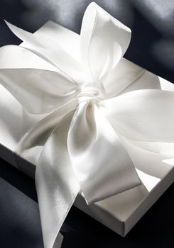 Anniversary celebration, shop sale promotion and luxe surprise concept - Luxury holiday white gift box with silk ribbon and bow on black background, luxe wedding or birthday present