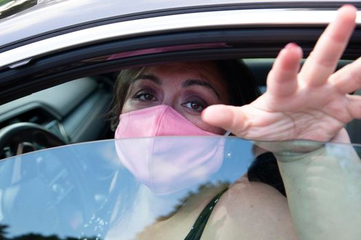 woman begging or pleading through a car window wearing a face mask 