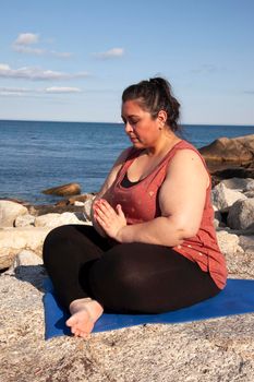 mindful woman by the sea with hands folded into prayer pose 