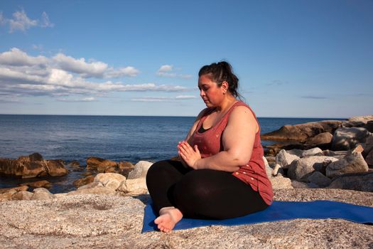 person by the ocean with hands folded in prayer or prayer pose for yoga 