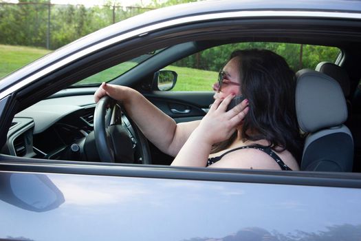 woman gabbing away on her cell phone while driving her car