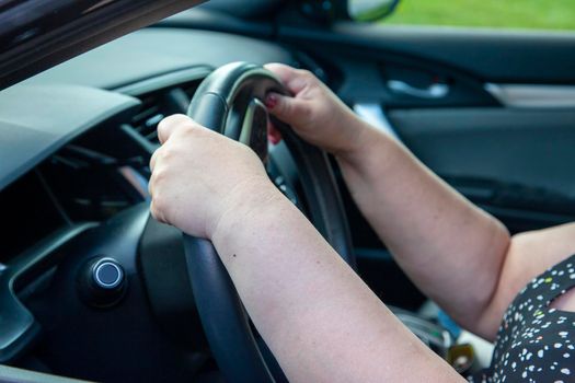 person's hands at the 10 and 2 position on the steering wheel while driving a car 