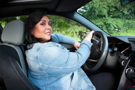 latina woman looking happy and calm while driving her car 