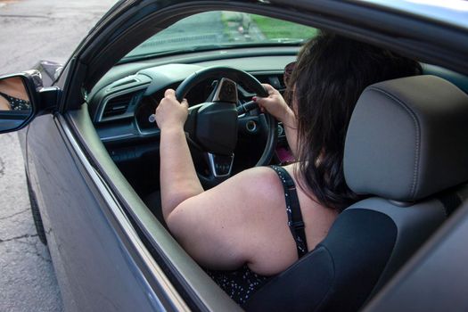 over the shoulder view of woman in her car with windows down 