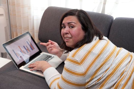 Woman at home points at her laptop showing a bar chart with results that are confusing