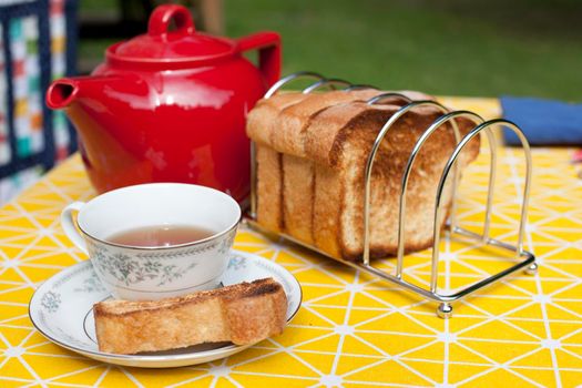 Having a snack or tea time outside with a tea pot, cup saucer and toast