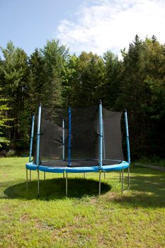 A blue and black contained trampoline area for children in the yard 