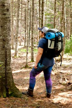 woman standing in the woods with her backpack, boots and gear