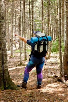 Person with hiking gear points in a direction while in the woods 