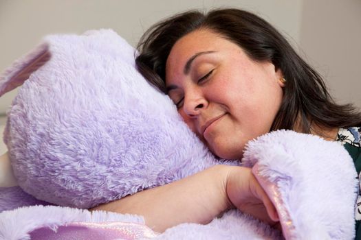happy adult woman with her huge purple stuffed animal is asleep or resting