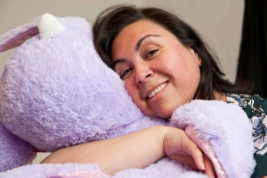 woman takes comfort in snuggling with a huge purple stuffed animal 