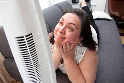 Laying in the heat at home, a person is happy to have their fan running to keep cool 