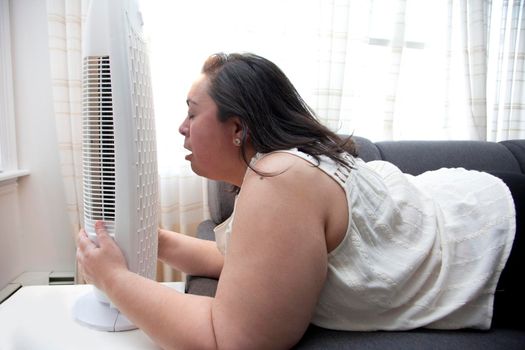Person with heat exhaustion clings to their fan inside at home 