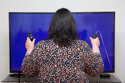 addicted to video games, a woman holds two controllers in her hands at home