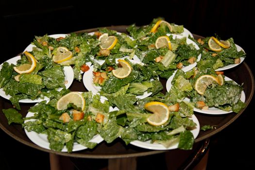 Several dishes of caesar salads with lemon and croutons ready to be served to guests