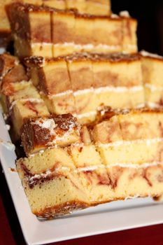  Fresh baked marble cake cut into finger sized pieces with icing on a serving plate