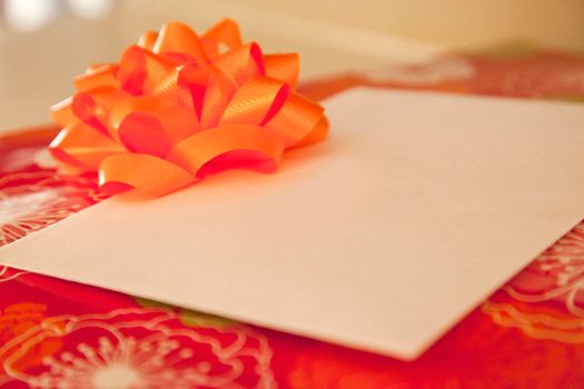 Red wrapping paper on a box with an orange bow and an envelope with copy space