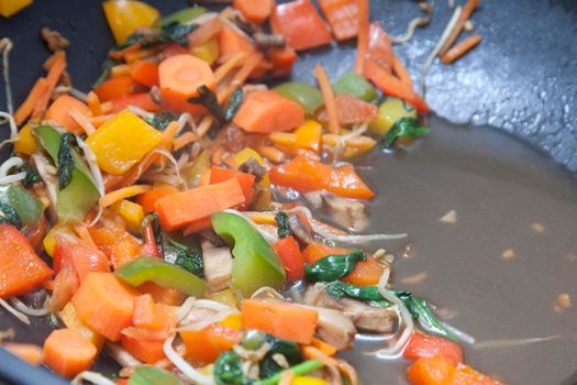 a skillet full of delicious healthy colorful food, with carrots, mushroom, peppers, onions