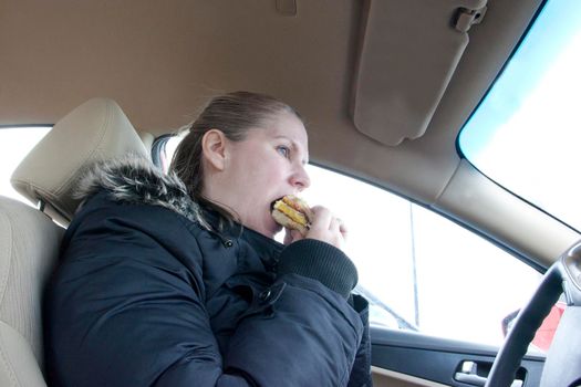 a woman eats a sandwich in her car 