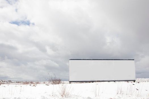  a white sign with copy space sits ready for billboard in a wide open winter meadow