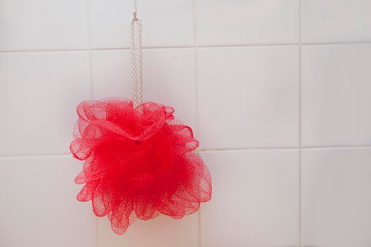 White tiled shower with a loofah scrubber on a rope