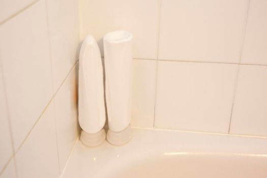a tile shower with two white blank bottles with shampoo or conditioner or body wash 