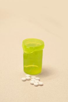 A yellow bottle of pills on the bathroom sink beside a handful of white medicine 