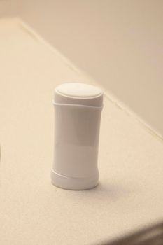 A white stick of deoderant or antiperspirant on the bathroom sink at home