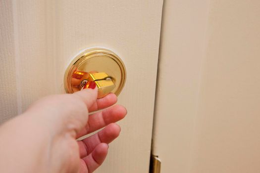  Hand unlocking a deadbolt on the inside of the apartment door 