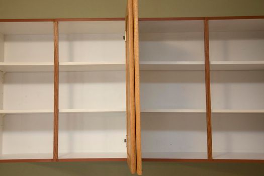 Empty bare kitchen shelves, in a vacant apartment or home with no food. 