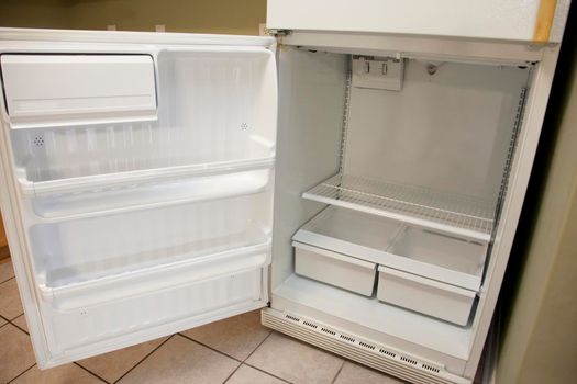 Kitchen fridge with an open door and bare, empty shelves