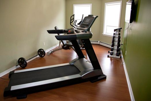 A treadmill in a home gym with other equipment inside an apartment or home