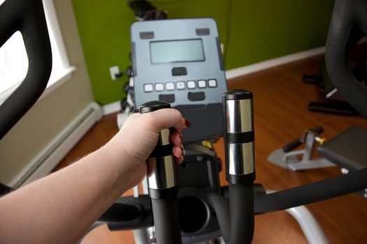 Hand on the elliptical machine at a home gym 