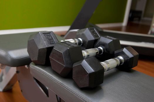 Three light weight dumbells on a bench 