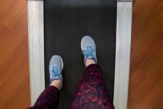 POV looking down at sneakers and workout pants on a treadmill ready to run 