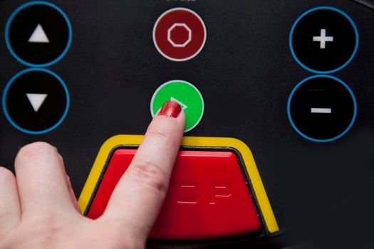 Hand pushes the green 'go' button on a treadmill, ready to run 