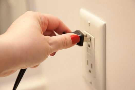 Hand pulls an electrical cord out of the wall to unplug the power