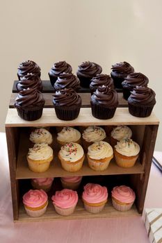 Chocolate, strawberry and vanilla cupcakes on a wooden table display 