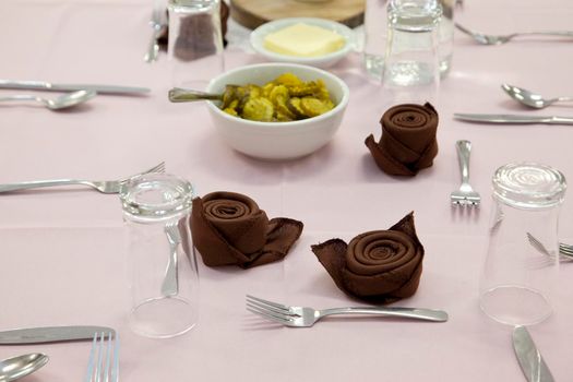 A table set with glasses, pickles, napkins, and utensils