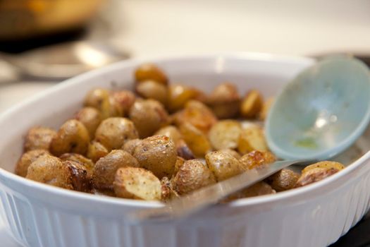 Yummy roasted potatoes in dish with serving ladle 
