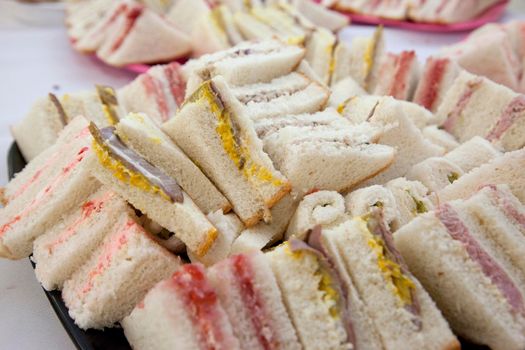 Delicious looking tiny triangle finger sandwiches at a party 